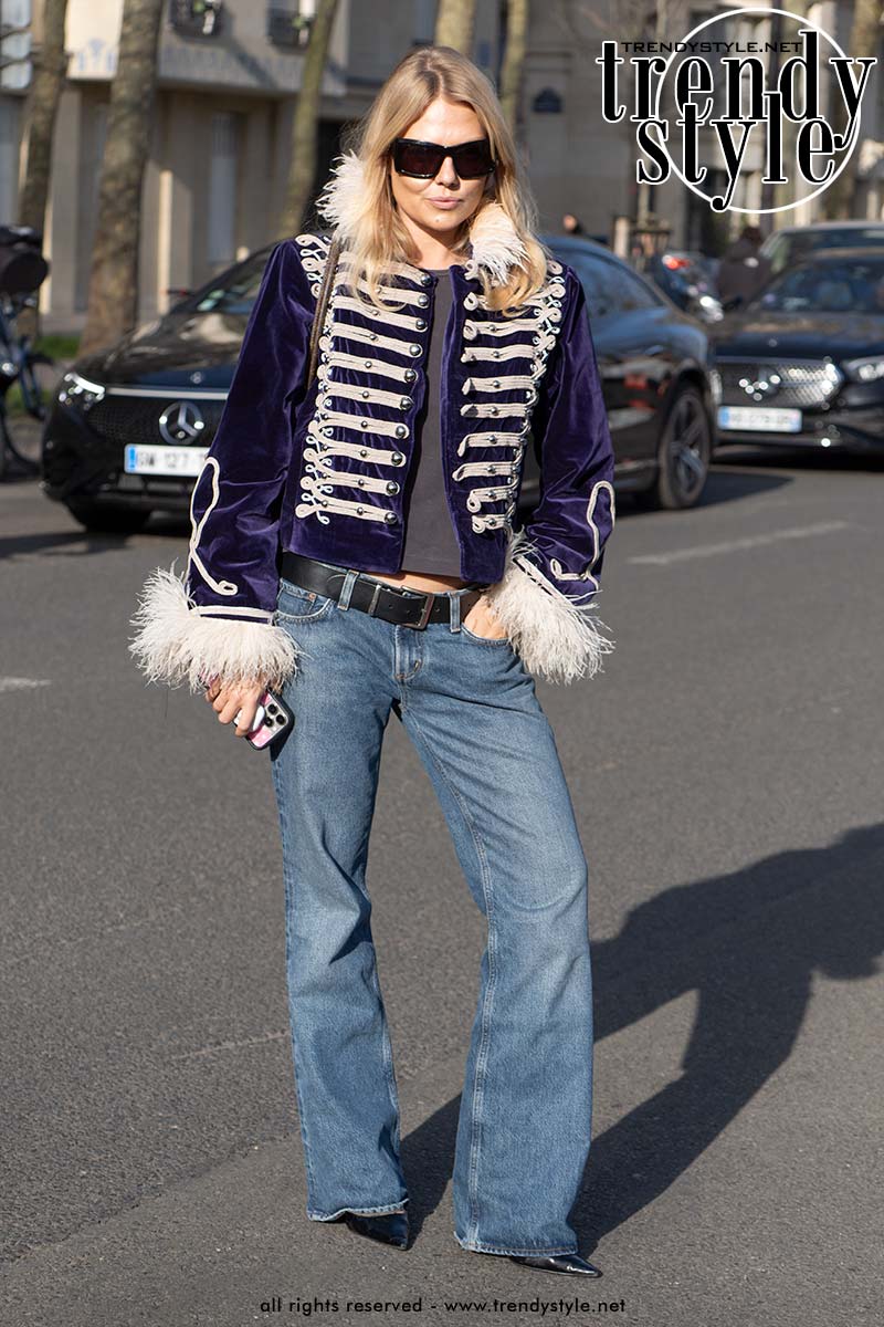 Streetstylelook met een donkerblauw fluwelen militair jasje met witte koorddetails en faux fur manchetten, gecombineerd met een wide leg jeans en puntige schoenen tijdens de Fashion Week. Foto Charlotte Mesman