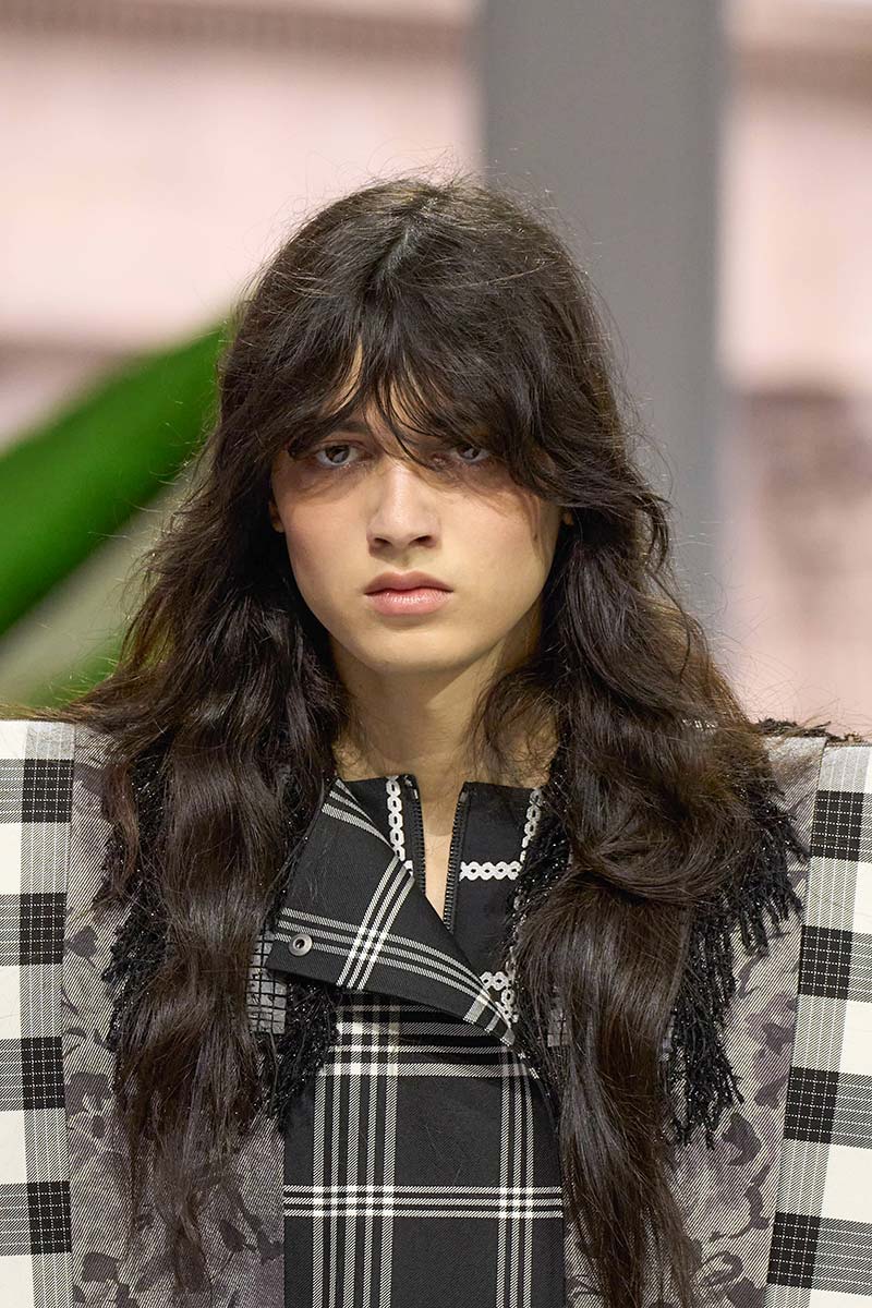 Model met lang krullend haar en butterfly cut op de catwalk van Louis Vuitton herfst winter 2026 2027. Photo courtesy of Louis Vuitton