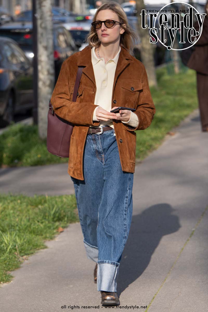 Gast bij Paris Fashion Week draagt een wijde spijkerbroek met brede omslag en een blazer. Foto Charlotte Mesman