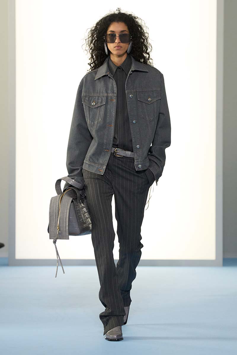 De krijtstreep wordt casual: een slim fit broek en bijbehorend overhemd met daarover een denim jack bij Sportmax. Let ook op de tas met krokodillenstructuur. Photo courtesy of Sportmax