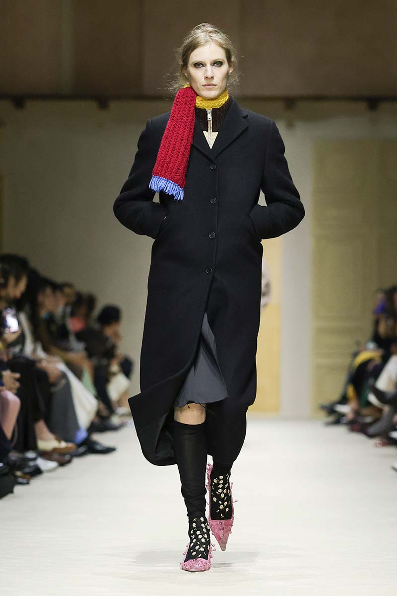 Lange winterjas met coltrui eronder en gebreide sjaal bij Prada. Photo courtesy of Prada