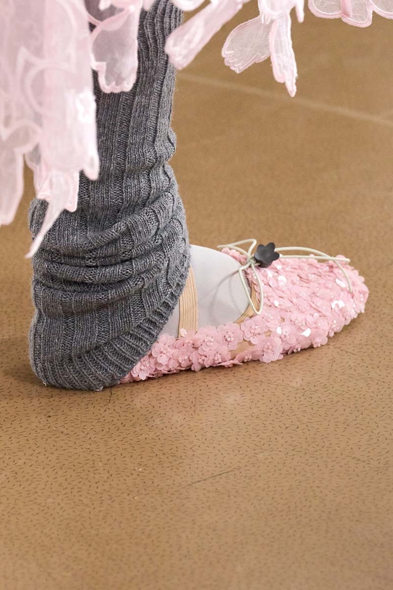 Close-up van grijze gebreide beenwarmers met ballerina’s met pailletten tijdens de catwalk van Cecile Bahnsen. Photo courtesy of Cecile Bahnsen