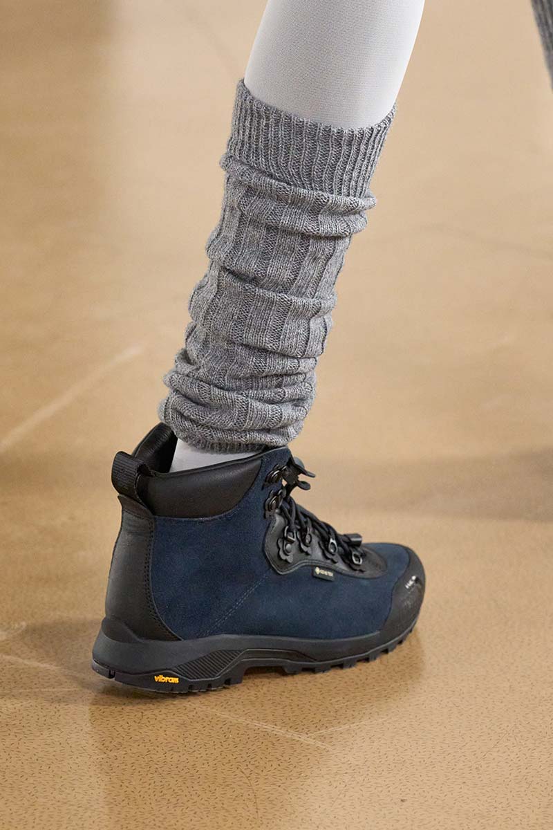Close-up van grijze gebreide beenwarmers met hoge wandelschoenen tijdens de catwalk van Cecile Bahnsen. Photo courtesy of Cecile Bahnsen