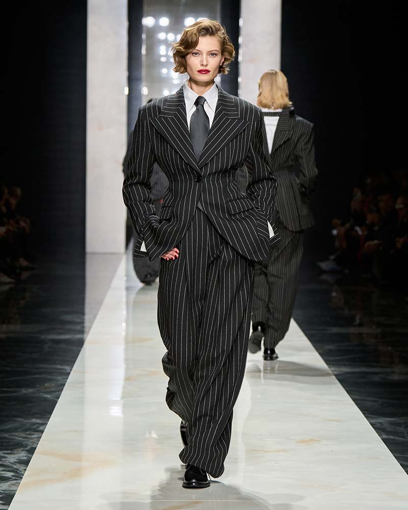 Donkergrijs pinstripe pak met gestructureerde blazer en brede revers op de catwalk van Dolce & Gabbana. Photo courtesy of Dolce & Gabbana