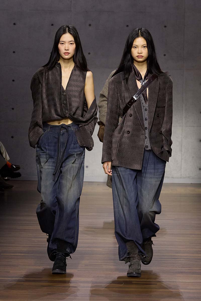 Modellen met superwijde donkere jeans, wijde bovenlagen en stevige suède halfhoge veterschoenen. Photo courtesy of Emporio Armani