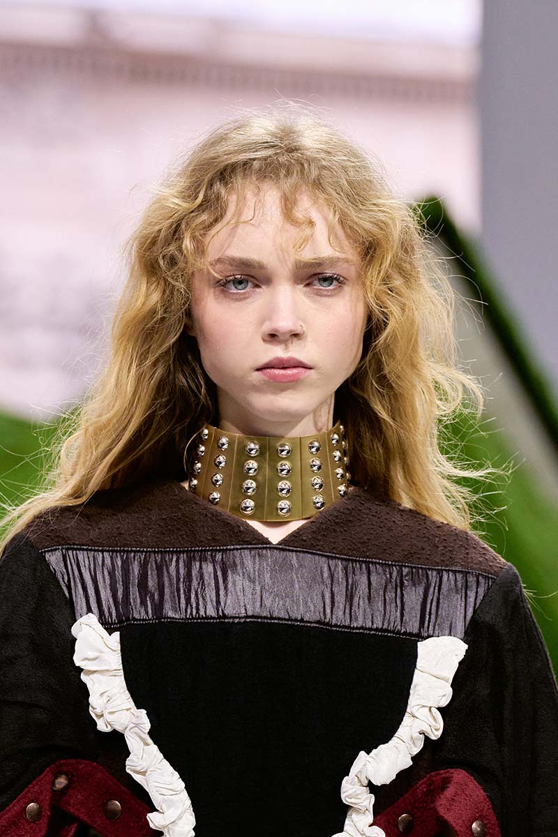 Catwalkmodel met lang haar, een luchtige krullende pony en een gewild slordige styling tijdens de Louis Vuitton-show voor herfst/winter 2026-2027. Photo courtesy of Louis Vuitton