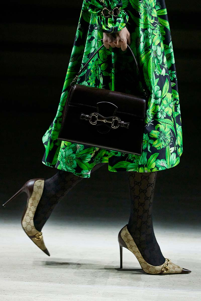 Typische Gucci-pumps met horsebit onder een rok met bloemenfantasie bij Gucci. Photo courtesy of Gucci