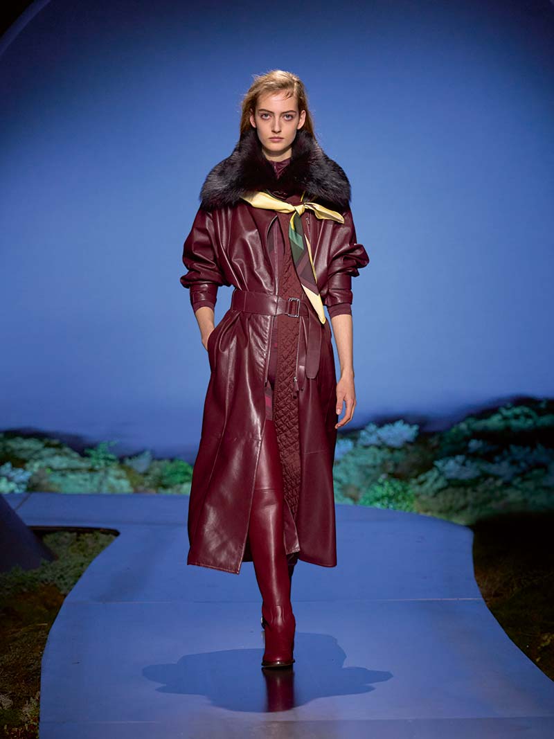 Slanke bordeauxrode puffer onder een leren jas met bontkraag op de catwalk van Hermès voor herfst winter 2026 2027. Photo courtesy of Hermès