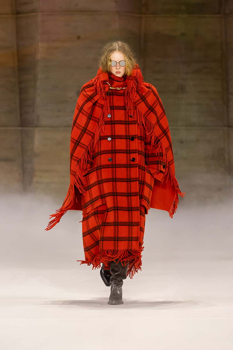 Lange rood-zwarte ruitenjas op de catwalk van Chloé voor herfst winter 2026 2027. Photo courtesy of Chloé