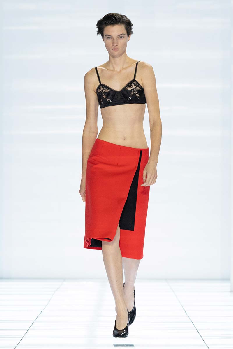 Rode knielange rok met zwarte opengewerkte beha bij Prada. Photo courtesy of Prada