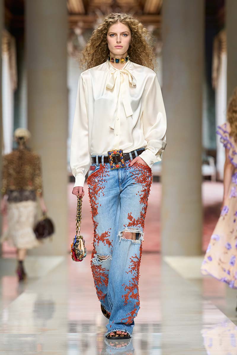 Spijkerbroek met koraalkleurige versieringen en witte blouse. Photo courtesy of Dolce & Gabbana