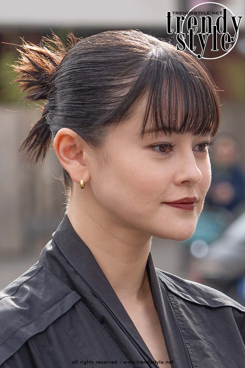 Strak kapsel met halfhoge knot en uitstekende haarpunten en lange pony. Foto Charlotte Mesman