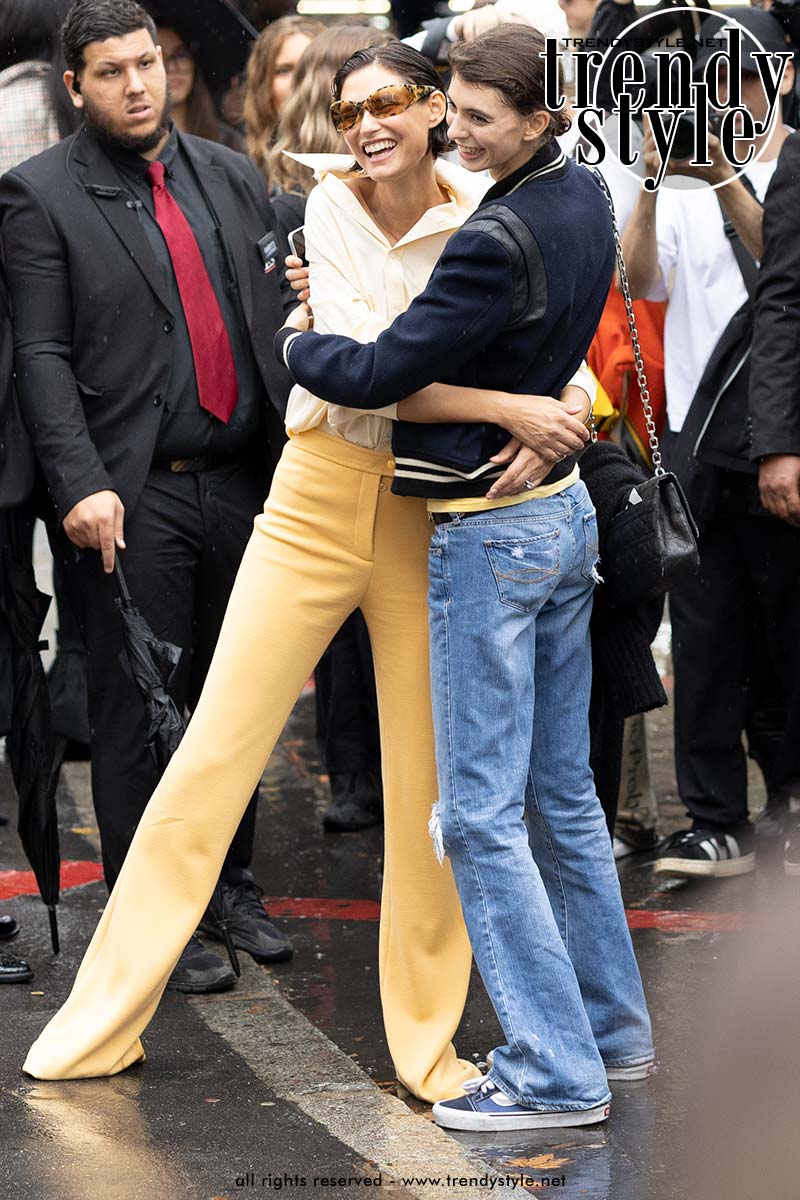 Bianca Balti in lange biscuitkleurige broek en crèmekleurige blouse en dochter Mathilde in jeans en Varsity jacket. Foto ADVERSUS