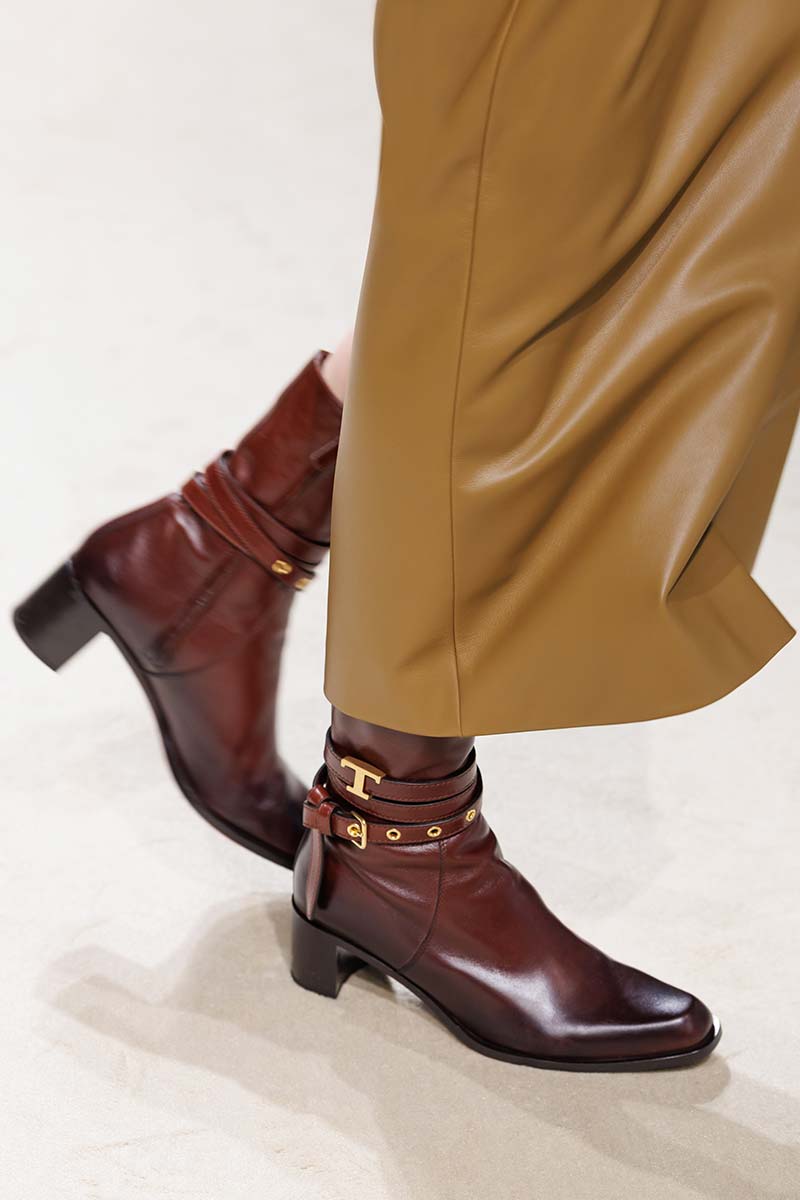 Klassieke enkellaars in het bruin met gesp en metallic logo onder enkellange rok. Photo courtesy of Tod's